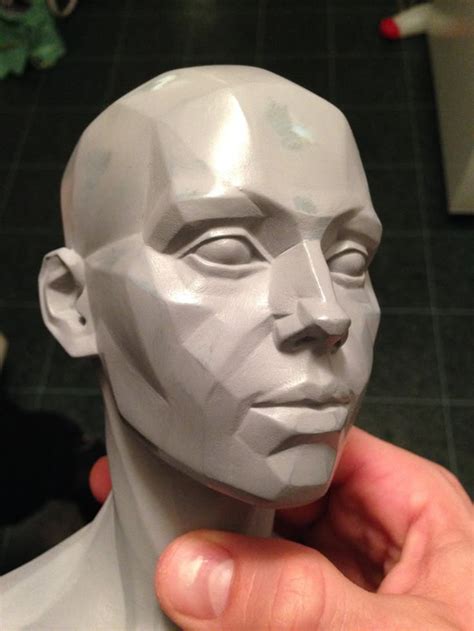 a person is holding up a sculpture of a man's head in front of the camera