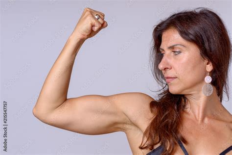 Strong fit mature woman flexing her arm muscles Stock Photo | Adobe Stock