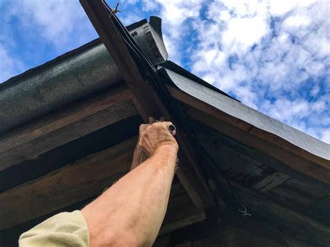 man repairs the roof at a height. manufacturing in a wooden house