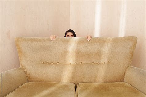 young woman hiding   retro couch  stocksy contributor ulas