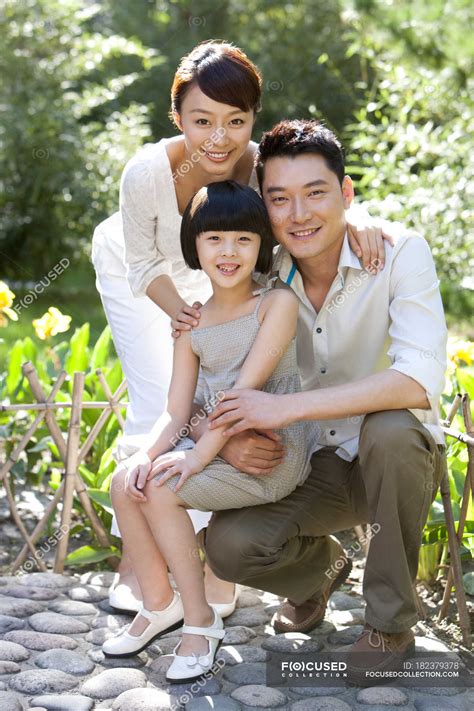 Portrait of Chinese family with daughter in garden — green, selective