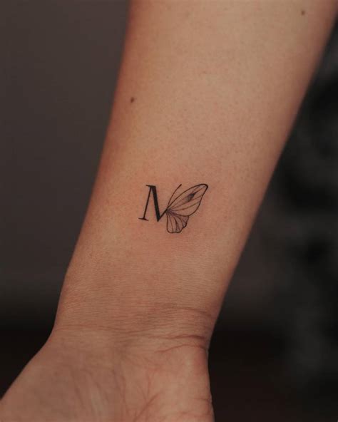 Tattoo of the letter "M" and butterfly located on the