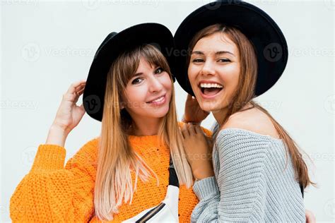 Two carefree girls sending Air kiss to camera , standing over white
