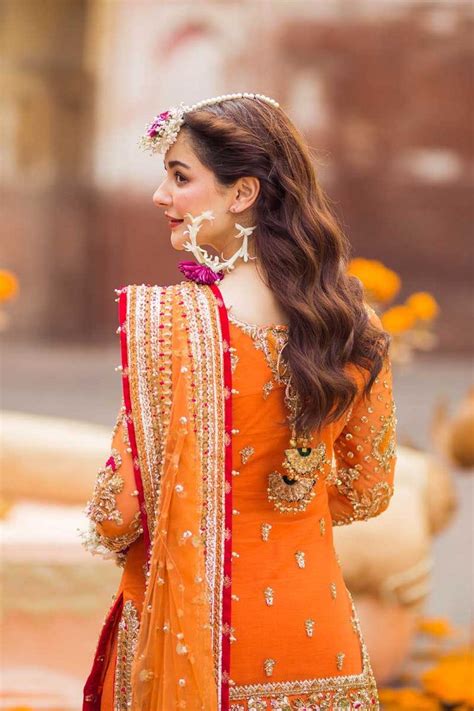 a woman in an orange and red outfit with flowers on her head, looking ...