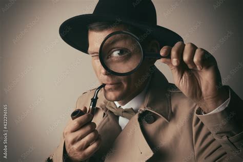 Male detective with smoking pipe looking through magnifying glass on beige background Stock ...