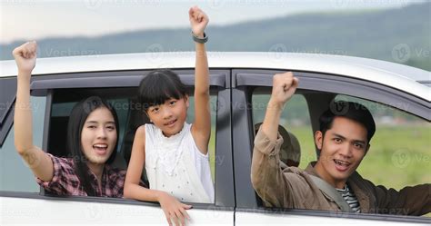 Happy little girl with asian family sitting in the car for enjoying