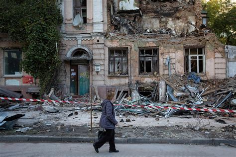 An elderly woman walks past an apartment building destroyed | HistoryNet