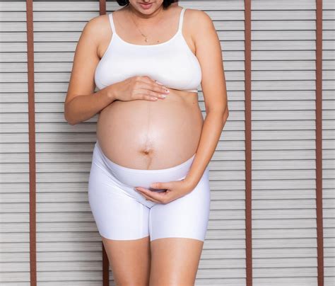 Portrait of a pregnant woman touching her big belly close up, mother