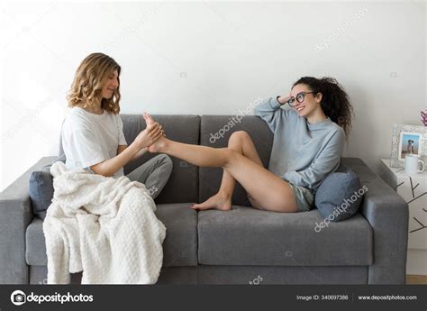 relaxed lesbian couple home  young woman giving feet massage stock