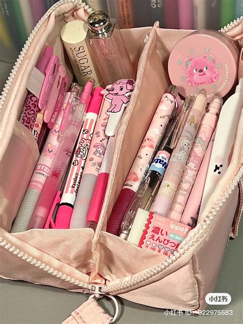 a pink bag filled with lots of different types of pens and pencils on ...