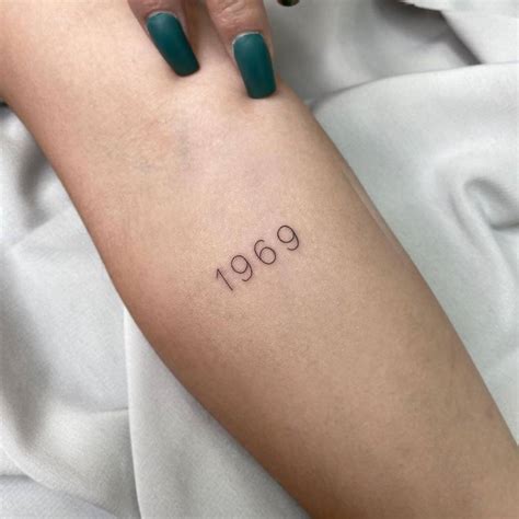 "1969" lettering tattoo on the inner forearm.