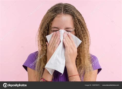 Cute young girl child sneezing in a tissue blowing his runny nose ...