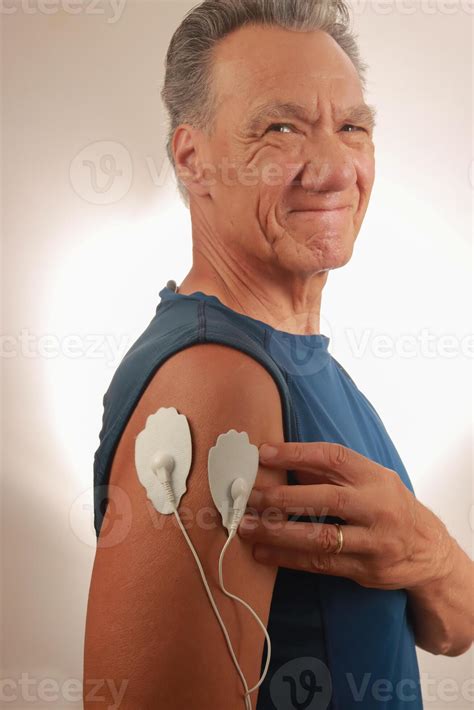 Man using an Electro Therapy Massager or Tens Unit on his Deltoids for