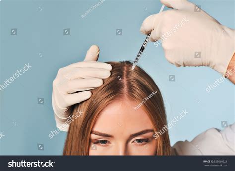 handsome woman receives injection head procedure stock photo