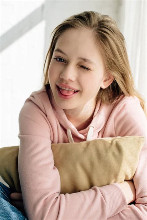 smiling teenage kid embracing brown cushion    camera