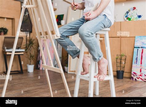 partial view of barefoot artist sitting on high chair in painting studio Stock Photo - Alamy