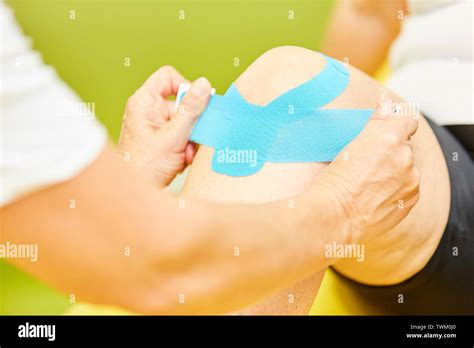 In Physiotherapy, a man gets a kinesio tape on his knee joint for knee ...