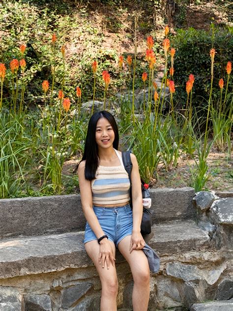 Arafed woman sitting on a stone wall with flowers in the background