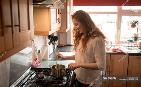 Beautiful woman cooking food in kitchen at home — self isolation, day ...