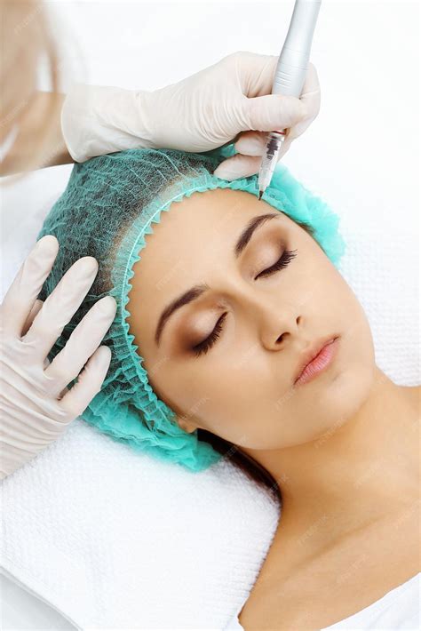 Esteticista profesional haciendo tatuaje de cejas en la cara de la