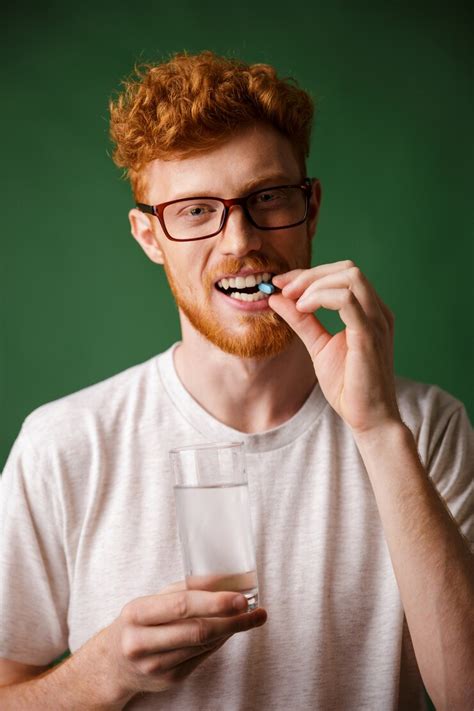 Free Photo | Portrait of a young redhead man in eyeglasses biting pill