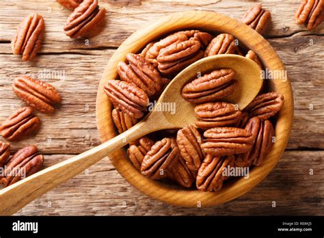 Raw pecan nuts in a bowl close-up on the table. horizontal top view