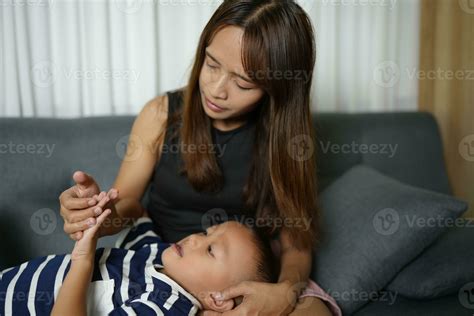 A son sleeps on his mother's lap inside the house. 32733995 Stock Photo