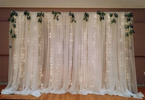 the curtain is decorated with greenery and lights