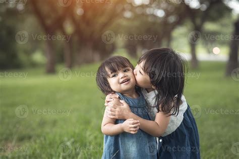 happy family. little girls sisters kissing and laughing in the summer