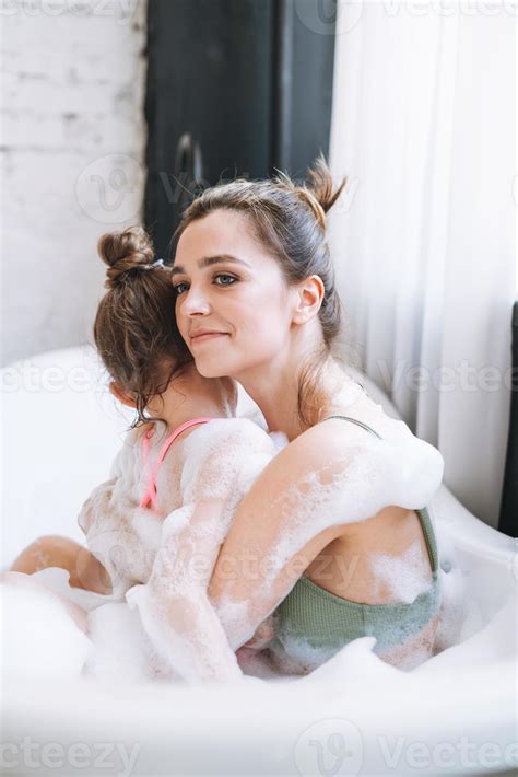 Young mother woman and little tween girl daughter having fun in bath