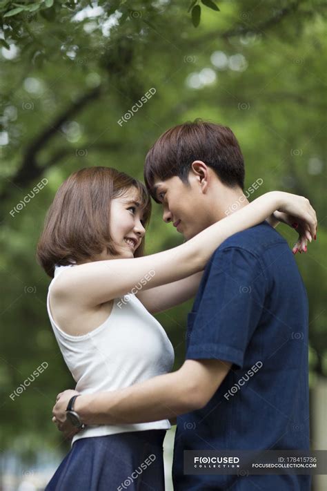 Young Chinese couple embracing in park — bonding, young couple - Stock