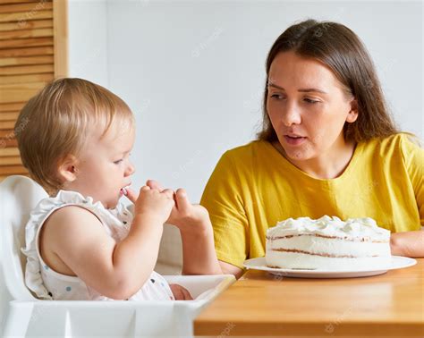 Premium Photo | Baby looking at creamy cake with interest while sucking