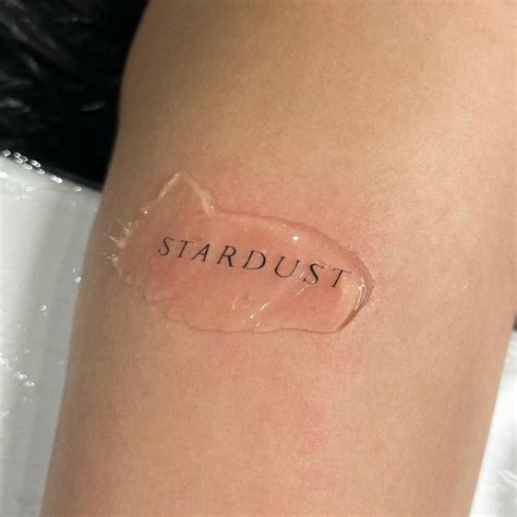 "Stardust" lettering tattoo located on the upper arm.