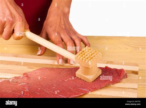 Tenderizing a raw steak with a kitchen hammer Stock Photo - Alamy