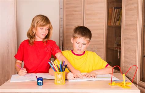 sister helping  brother  home assignment portrait   stock